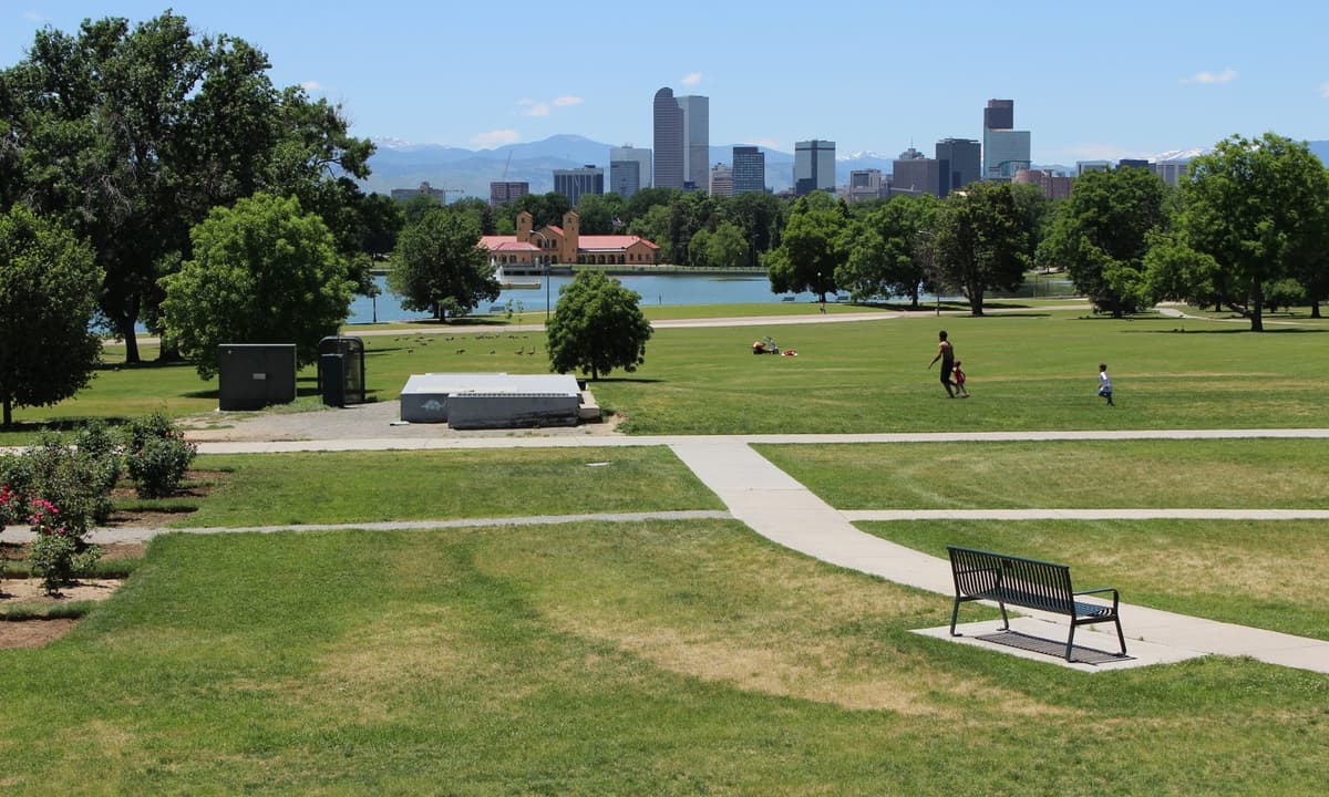 City Park on Park Hill's western edge — Ferril Lake and open lawns with the downtown Denver skyline and the mountains beyond