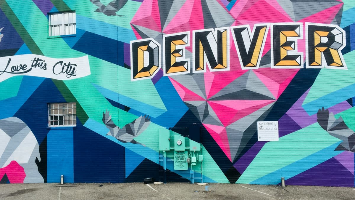 A colorful 'Love this City / DENVER' street mural on a brick wall in Denver's RiNo Art District